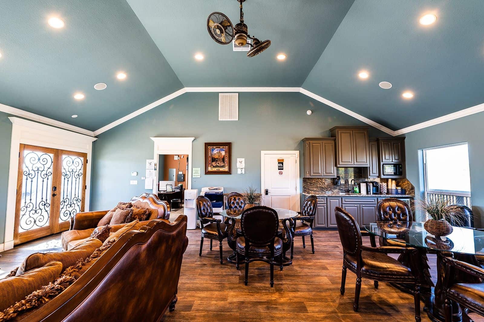 Clubhouse interior with dining tables, leather chairs, and kitchen