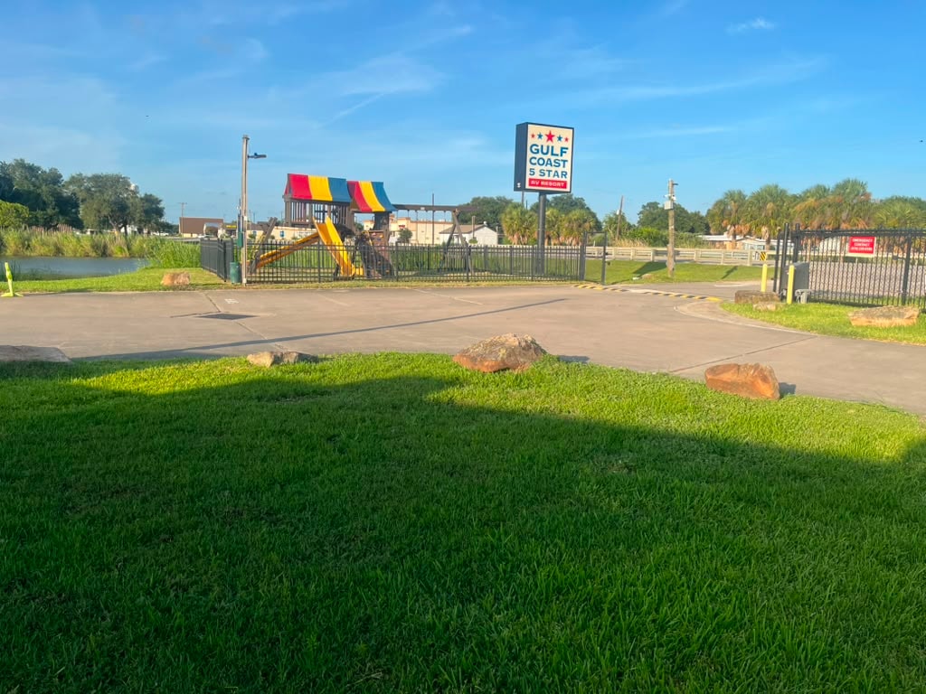 Gulf Coast 5 Star RV Resort entrance sign with playground, palm trees, and lush landscaping