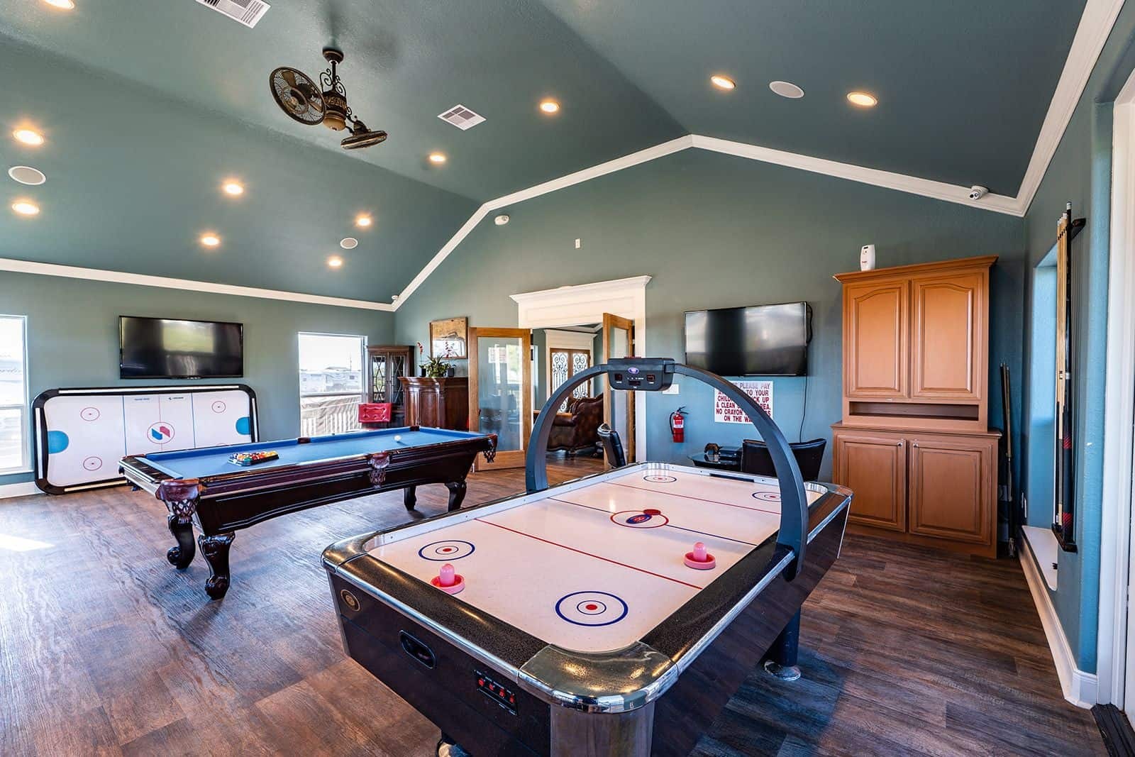Game room with pool table, air hockey, and flat-screen TVs