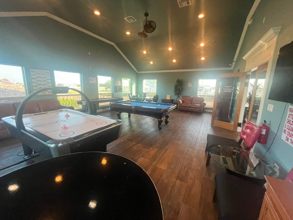 Game room with air hockey table in foreground, pool table behind, and lounge seating along the walls