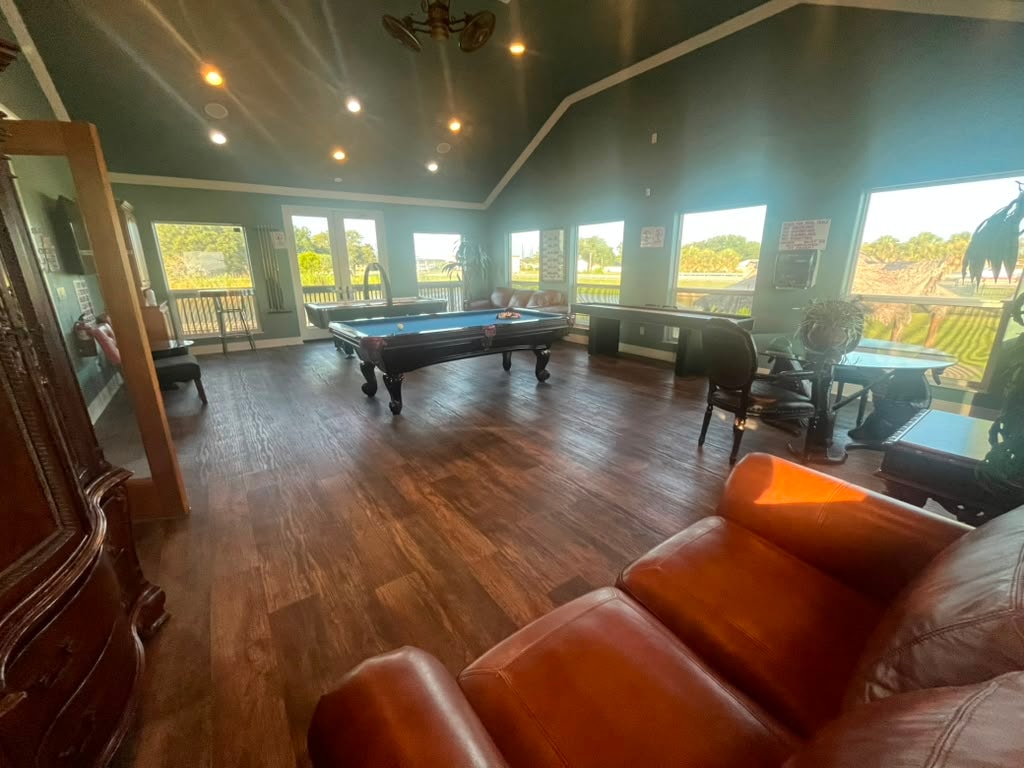 Game room with pool table centered, leather sofa in foreground, and resort views through large windows