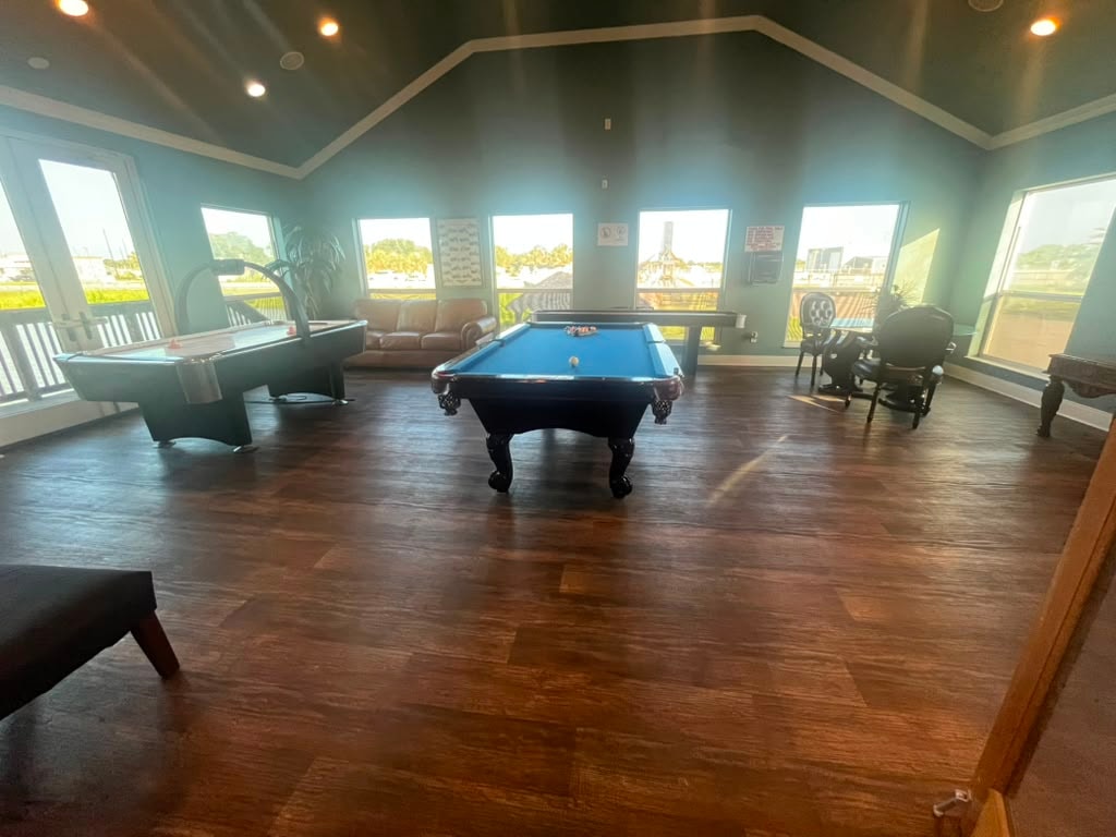 Wide game room with pool table, air hockey, shuffleboard, leather seating, and panoramic windows