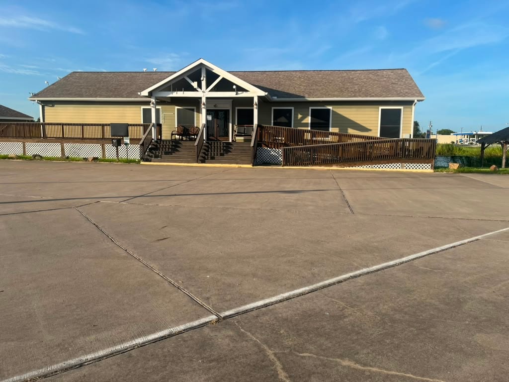 Main clubhouse building front exterior with covered deck, wood railings, and ADA ramp
