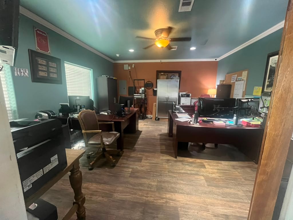 Resort office interior with staff desks, computers, wood floors, and teal walls
