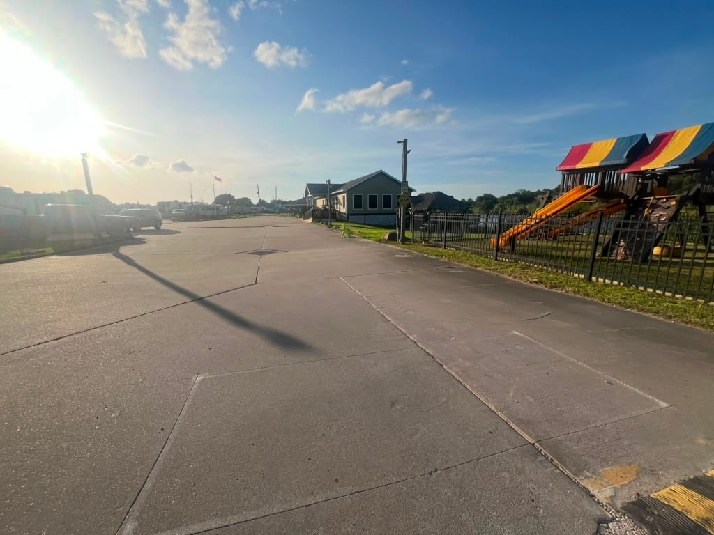 Wide concrete resort road at golden hour with playground and clubhouse visible in background