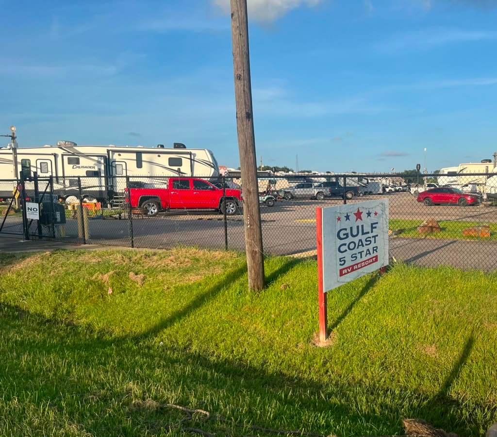 Gulf Coast 5 Star RV Resort sign with Crusader fifth-wheel and RVs behind security fence